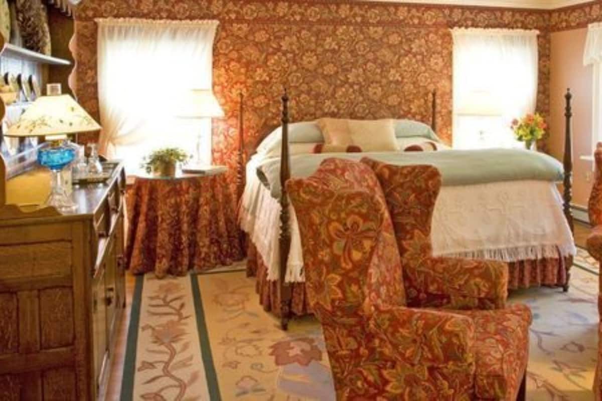 A traditional bedroom with a bed, two chairs, a nightstand, and a dresser.