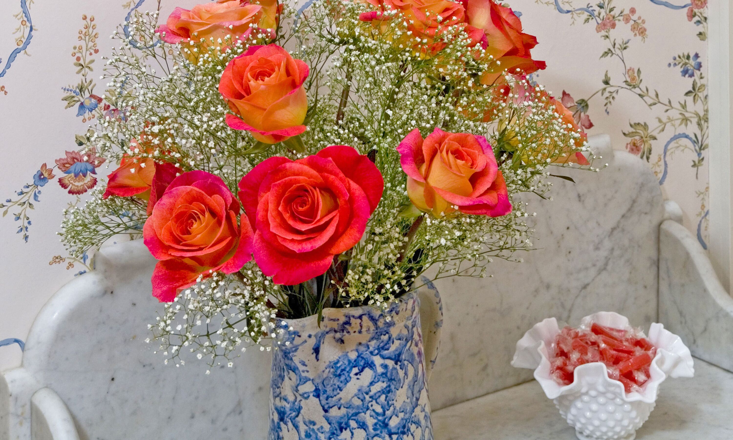 A vase with a floral arrangement of roses and baby's breath.