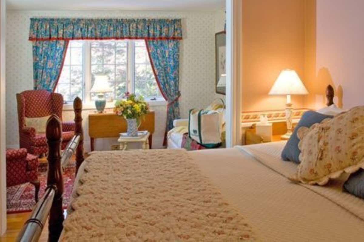 A hotel room with a large bed, a chair, a desk, and a window with curtains.