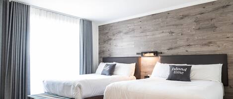 Habitación de hotel con dos camas, un banco y una pared de madera decorativa.