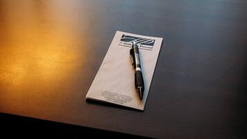 A dark wooden table with a pen and a hotel brochure.