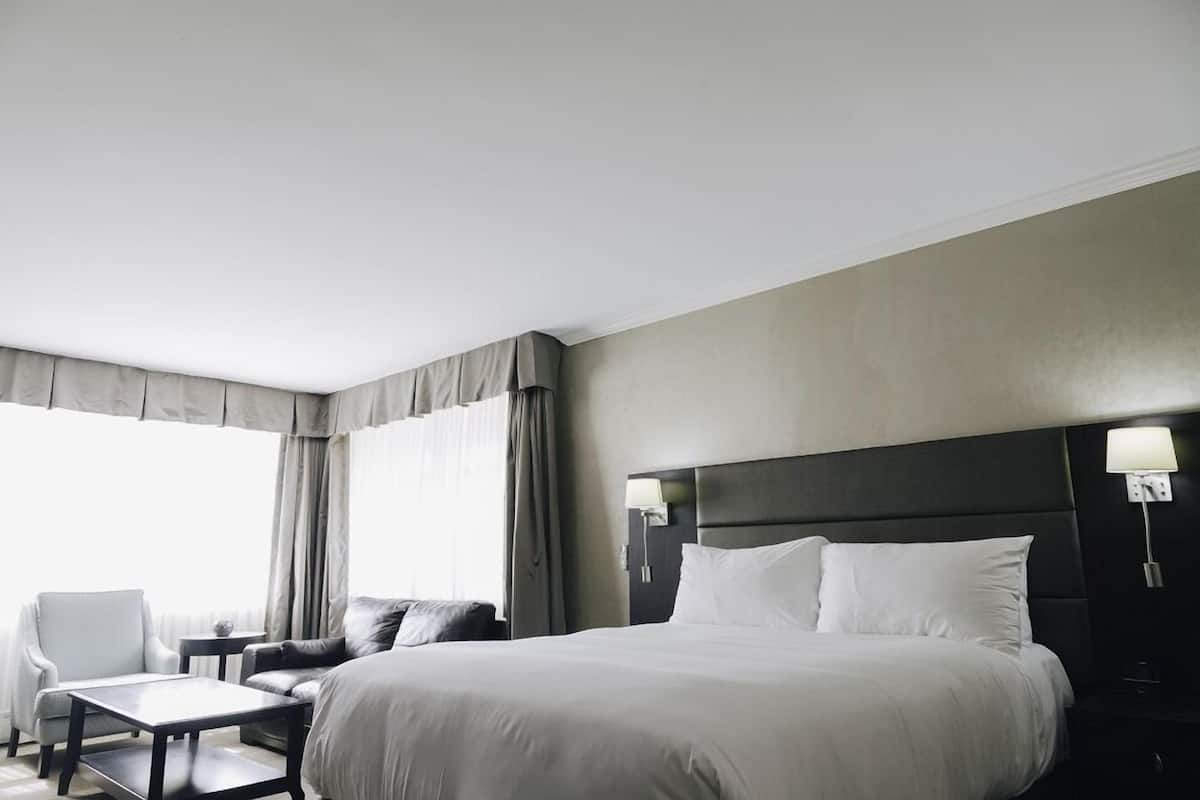 Quarto de hotel com uma cama grande, um sofá, uma mesinha e uma cadeira.