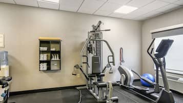 A gym with exercise equipment, a water cooler, and a window with blinds.