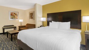 Camera d'albergo con un letto grande, due comodini, una poltrona e due lampade a parete.