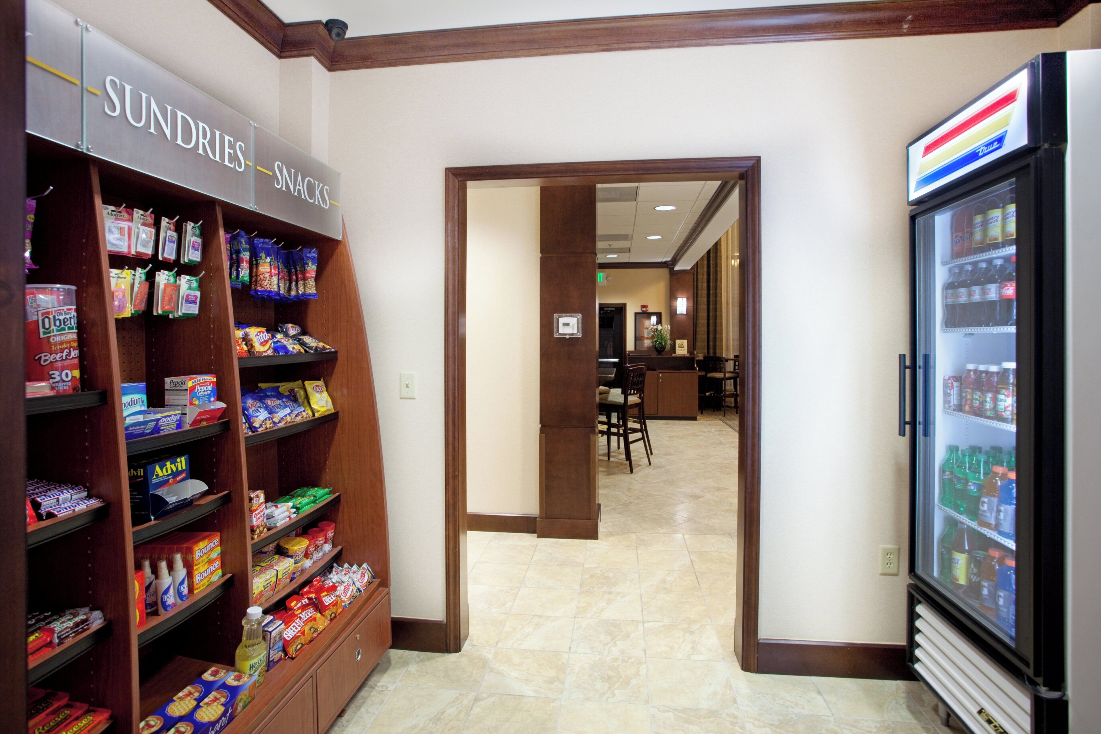 A corridor with snack shelves on the left and a beverage refrigerator on the right.