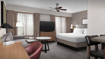 Una camera d'albergo con un letto, una televisione, un divano, una scrivania e una sedia.