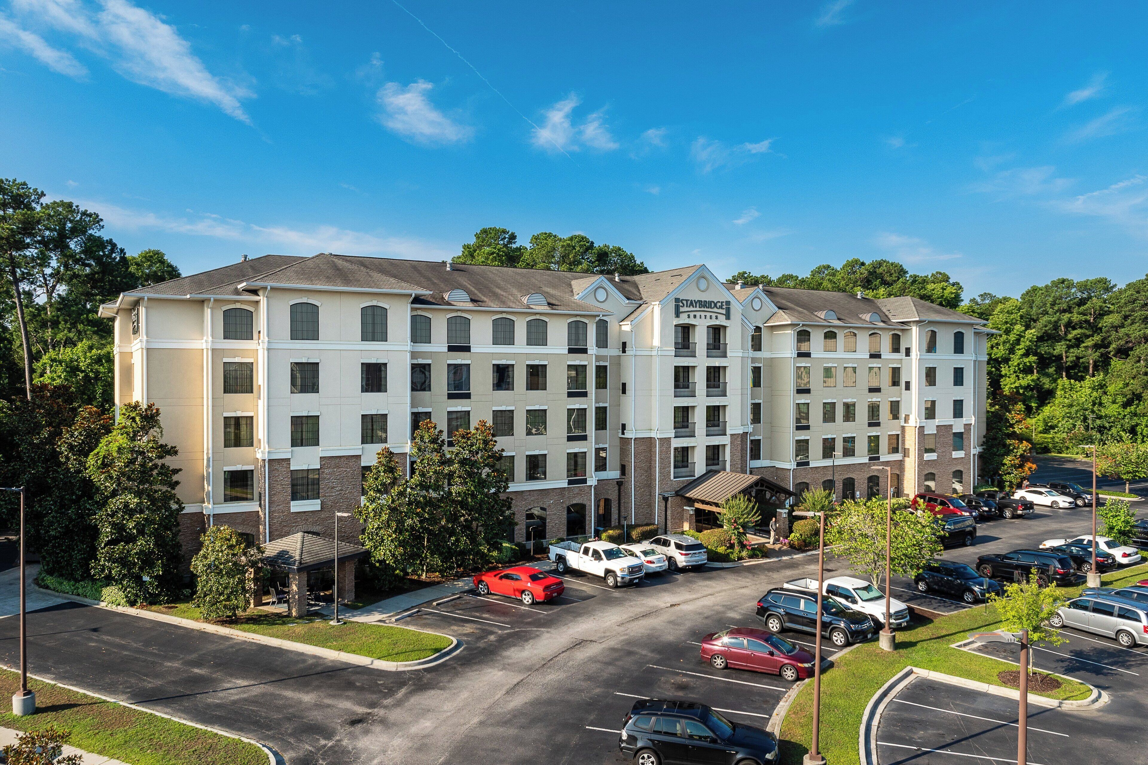 A multi-story hotel with a parking lot and a covered outdoor area.