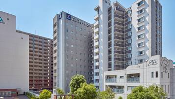 Un hotel de varios pisos con un diseño moderno, con balcones, una terraza en la azotea y un área de juegos.