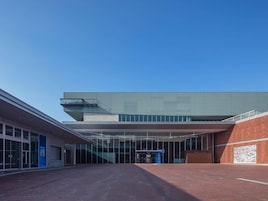 A modern building with a flat roof, large windows, and a brick facade.