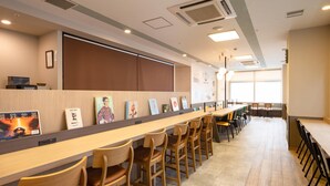 A long wooden table with chairs, a bulletin board with books, and a large window in a room with a tiled floor. - Comfort Hotel Kure (Kure)