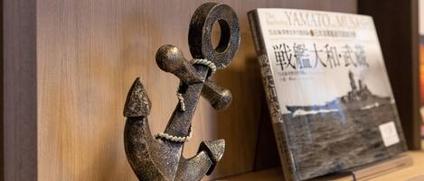 A wooden shelf with a metal anchor sculpture and a book titled 'The Battle of YAMATO MUSASHI'.