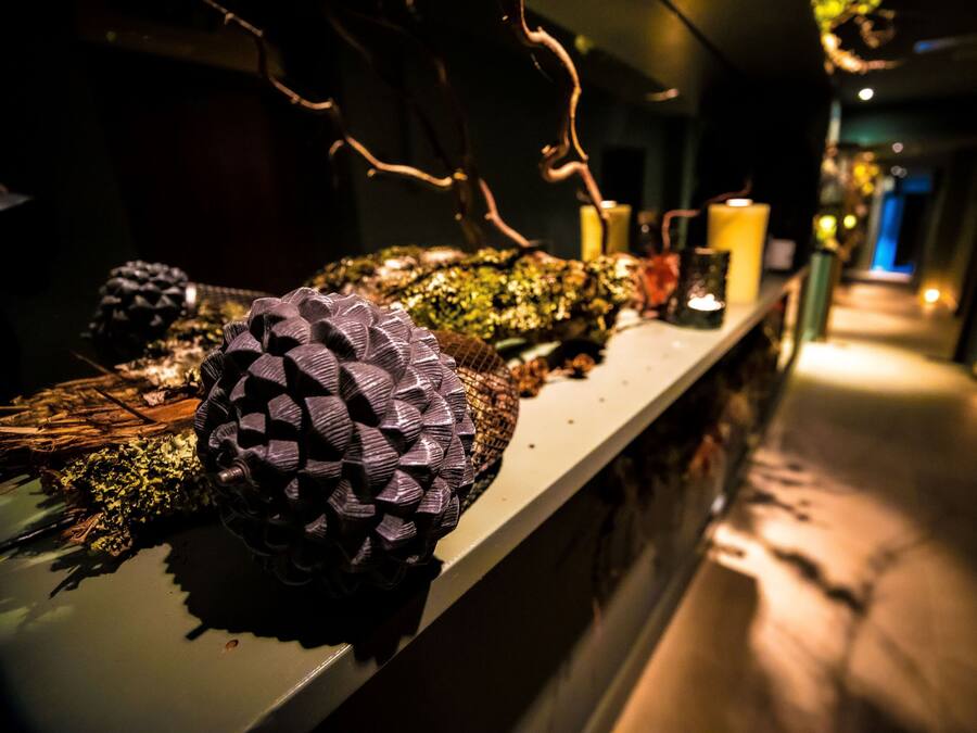 Un pasillo con un arreglo decorativo de piñas y ramas sobre un mostrador.