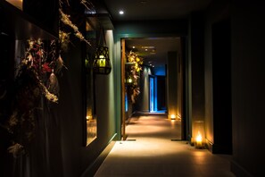 A dimly lit hallway with a warm light source at the end, a hanging plant, and a wall-mounted light fixture. - No. 1 Pery Square Hotel & Spa (Limerick)