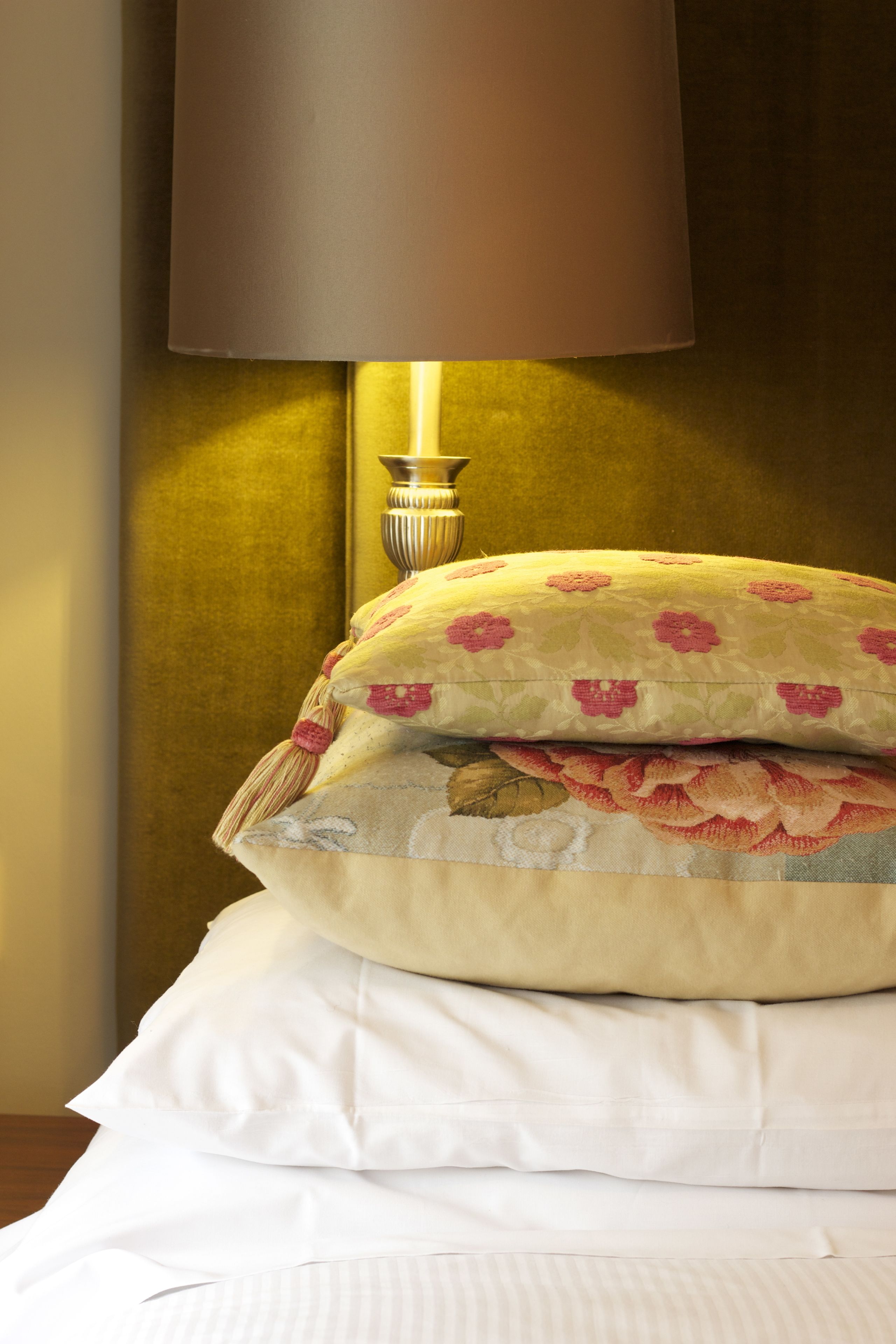A bed with multiple pillows and a lamp.