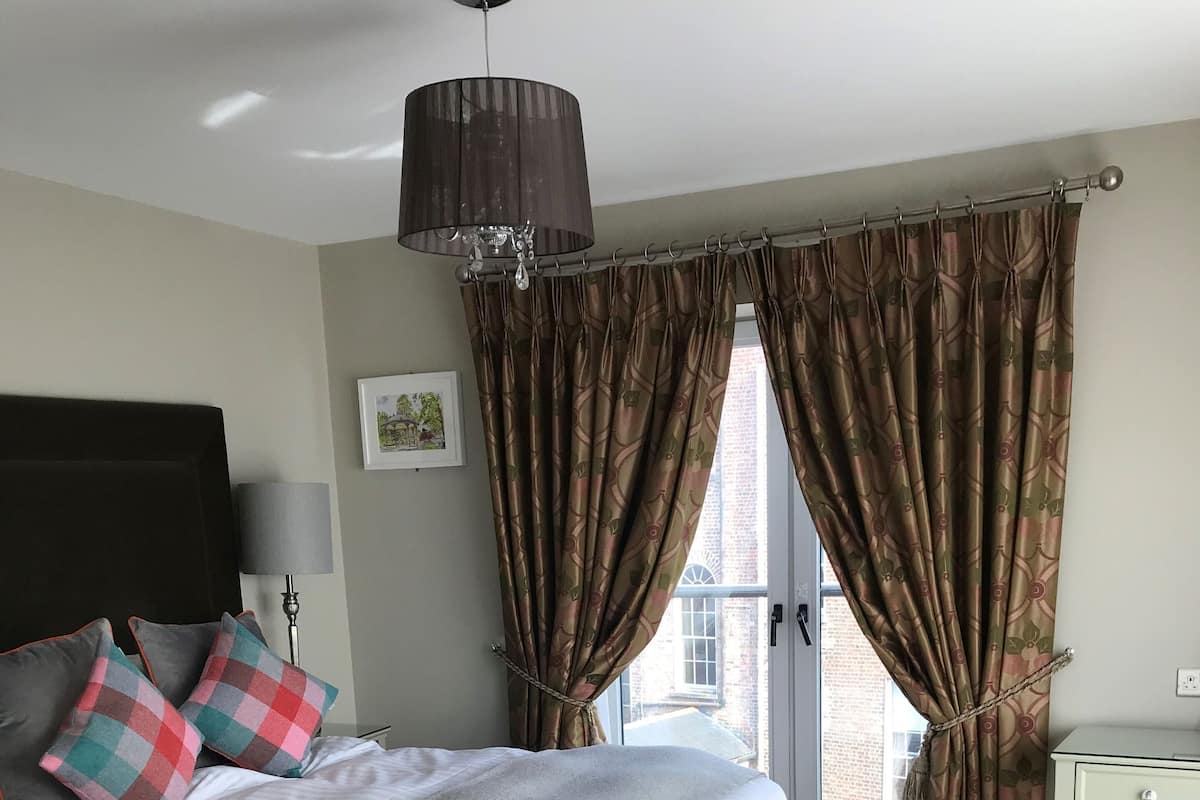 Un dormitorio con cama, escritorio y ventana con cortinas.