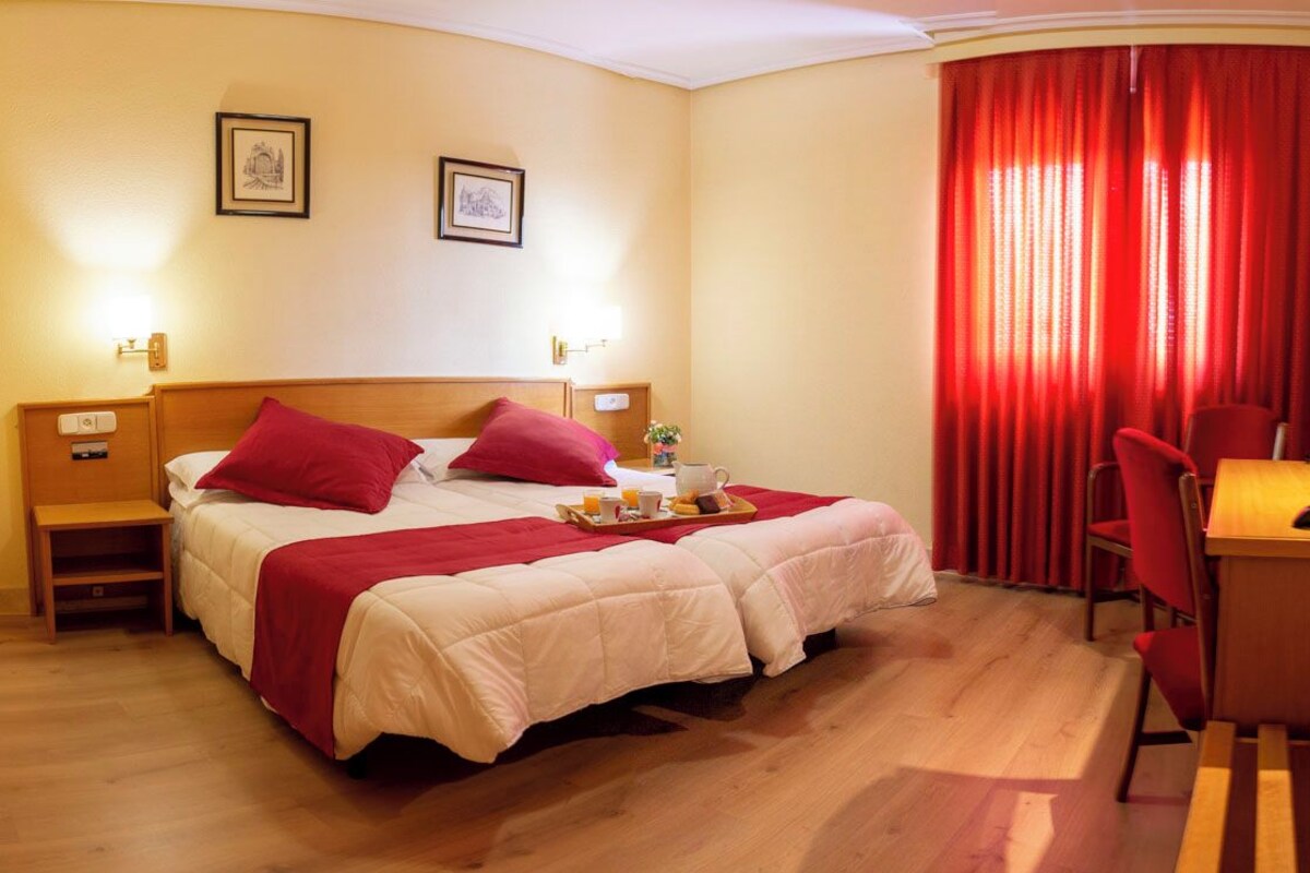 Ein Hotelzimmer mit Bett, Schreibtisch, Stuhl und Fernseher.
