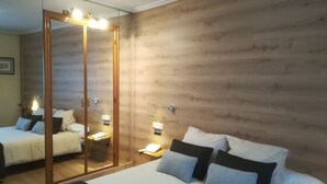 Habitación de hotel con una cama grande, pared de madera, espejo y mesita de noche con lámpara.