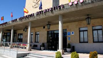Exterior del Hotel Residencia Helmantico, con entrada despejada, zona de estar al aire libre y banderas.