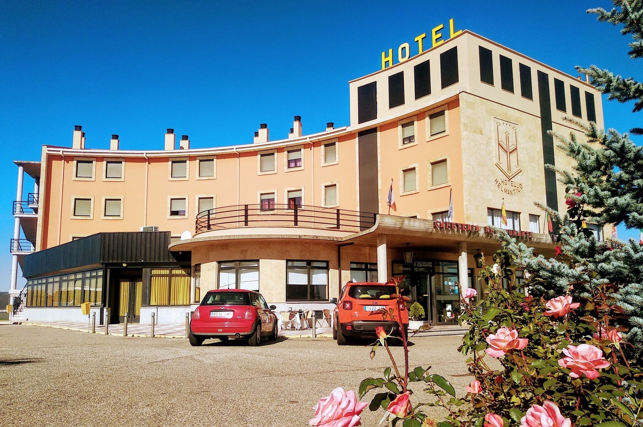 A hotel with a curved facade, a balcony, and a sign indicating it is a hotel.