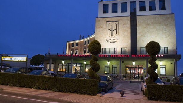 Un hotel con fachada moderna, un logotipo destacado y un cartel que indica que es un restaurante.