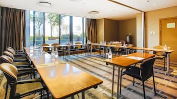 A conference room with long tables, chairs, and a large window with curtains.