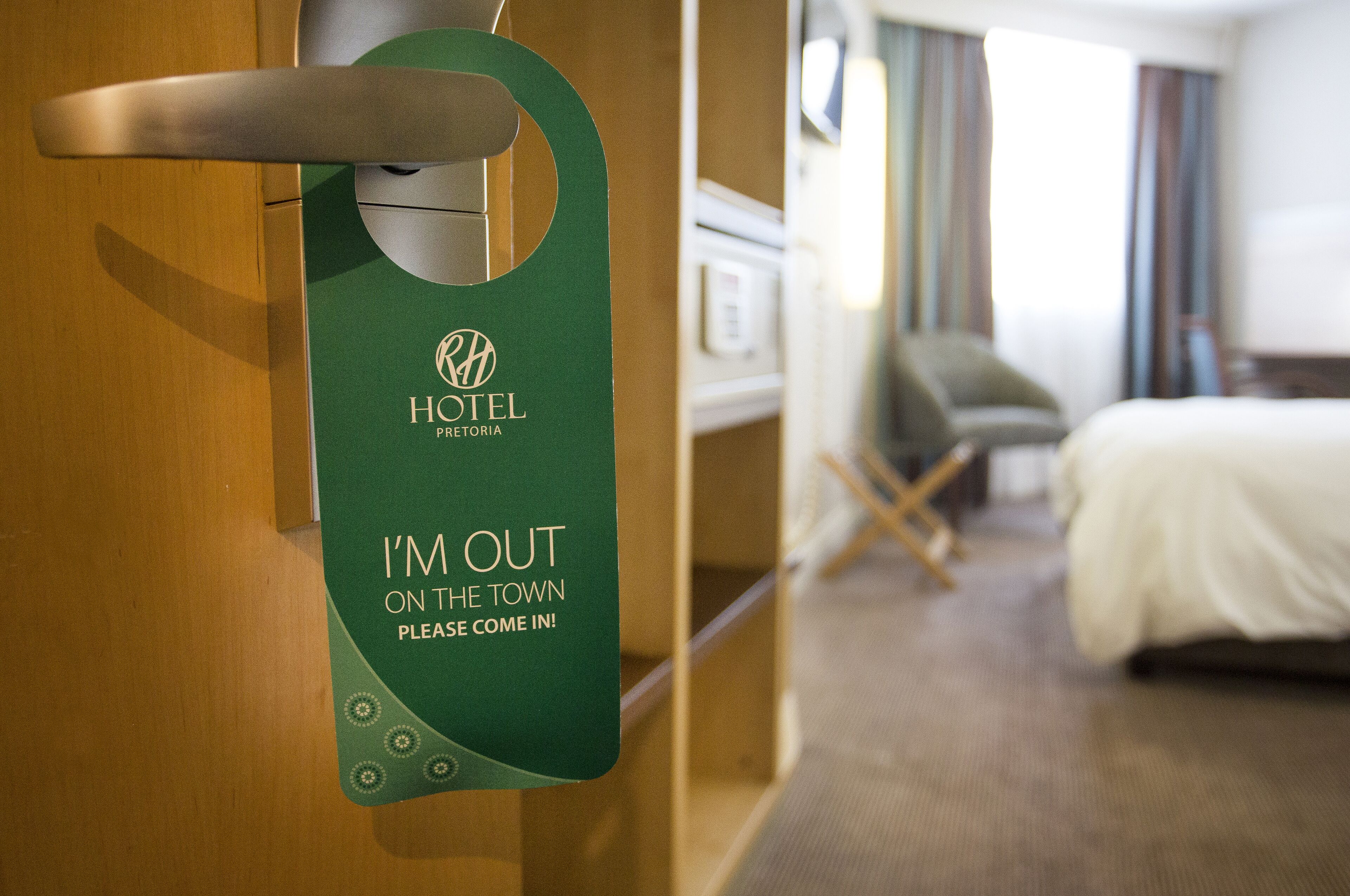 A hotel room door with a sign indicating the guest is out and inviting others to come in.