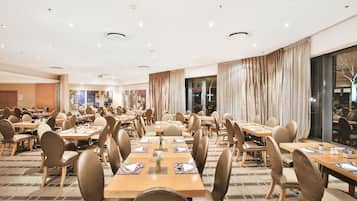 Une grande salle à manger avec de nombreuses tables et chaises, disposées dans un espace bien aménagé.