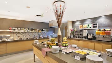 Un área de bufé con diferentes alimentos y un jarrón decorativo.