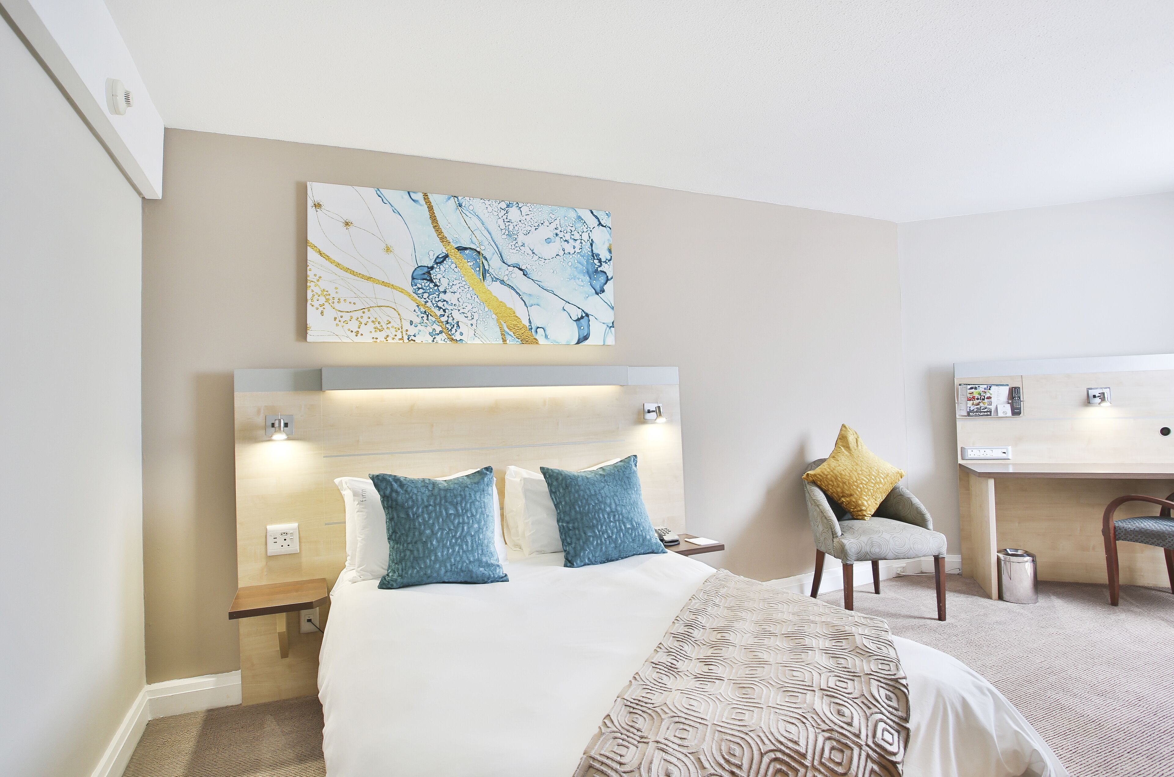 Une chambre d’hôtel avec un lit, un bureau et une chaise.