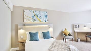 Une chambre d’hôtel avec un lit, un bureau et une chaise.