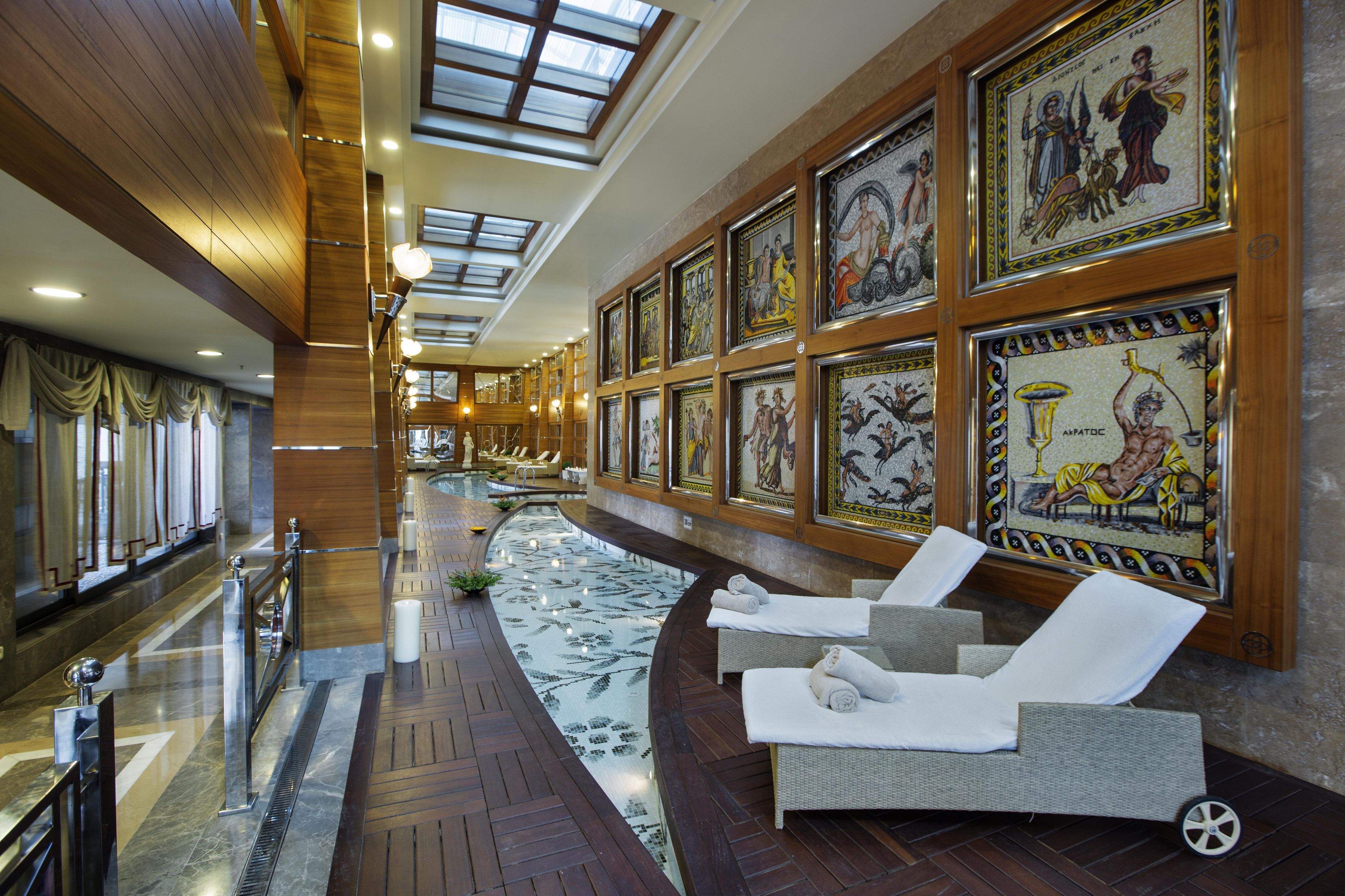 A spa area with a pool, lounge chairs, and artwork on the walls.