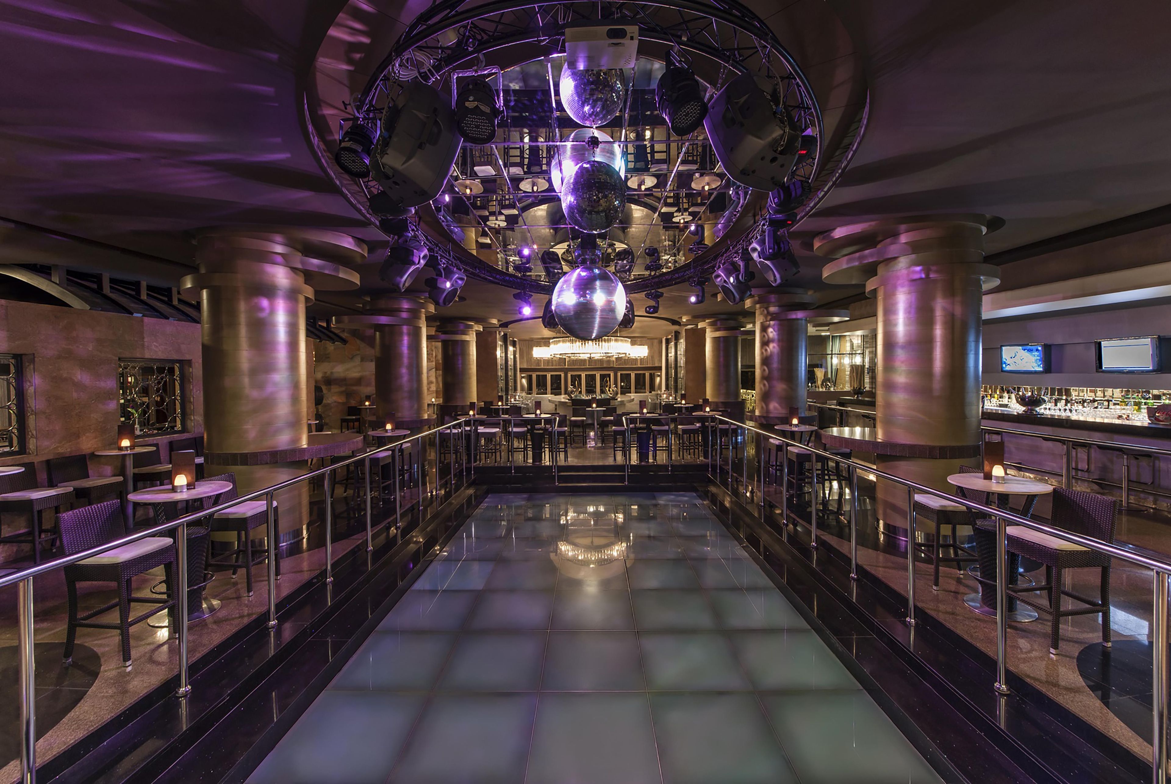 A spacious indoor area with a central open space, surrounded by tables and chairs, and a bar area with a counter.