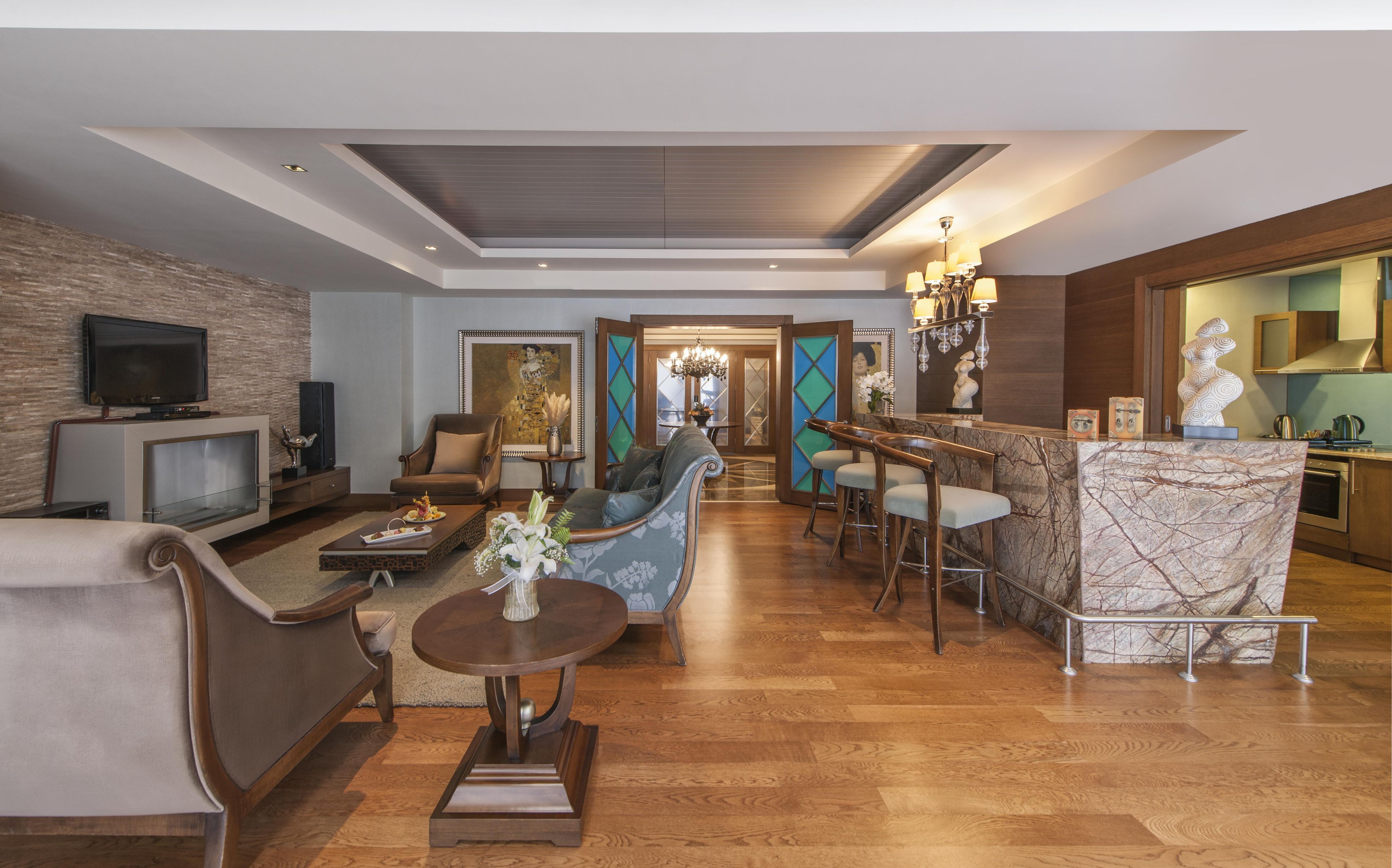 A modern living room with a television, seating, a dining area, and a kitchen.