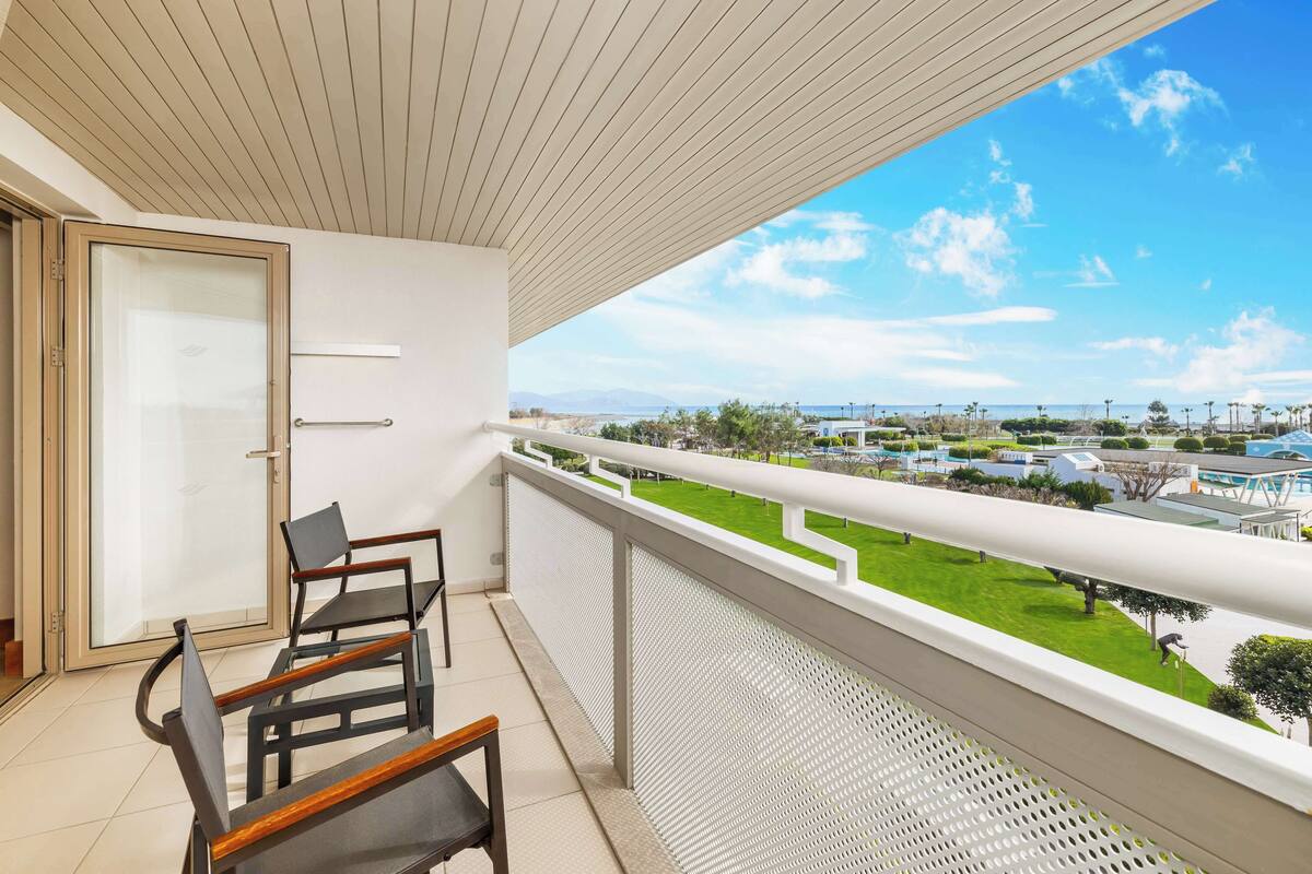 Een balkon met uitzicht op een groen gazon en gebouwen in de verte.