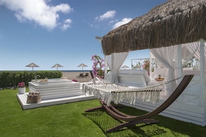 Una zona relax in spiaggia con un'amaca, un'area salotto e una piscina.