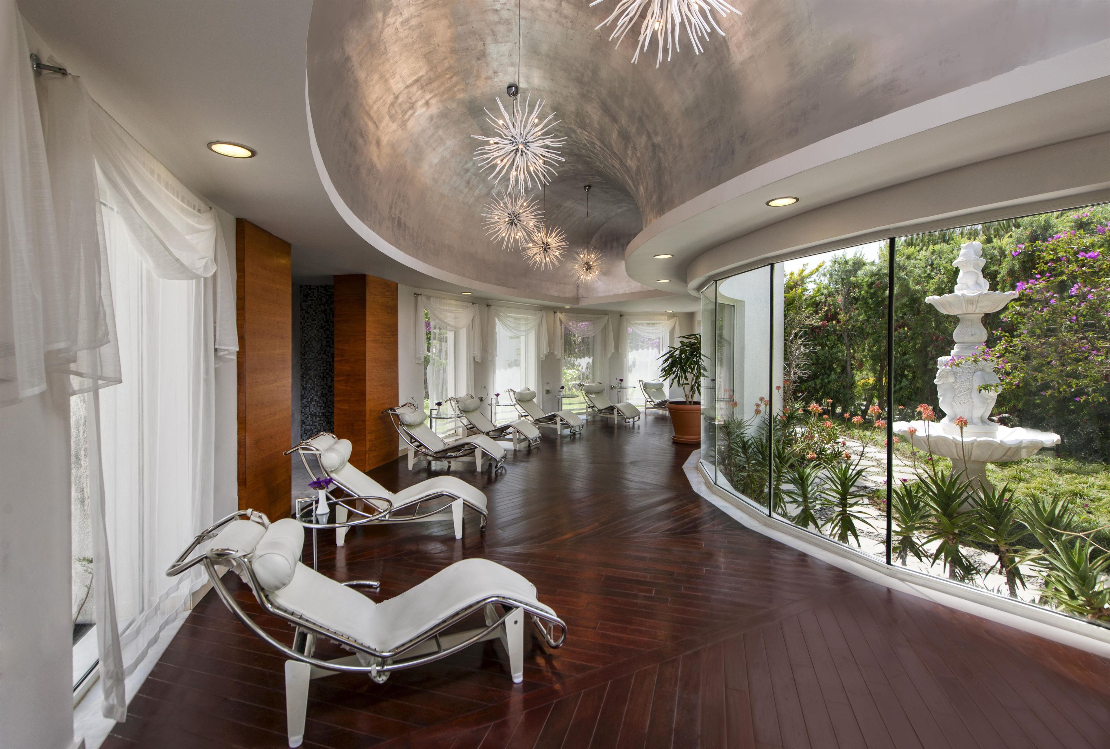 Un spa moderne doté de fauteuils inclinables, d’une grande fenêtre et d’un plafond orné de luminaires originaux.
