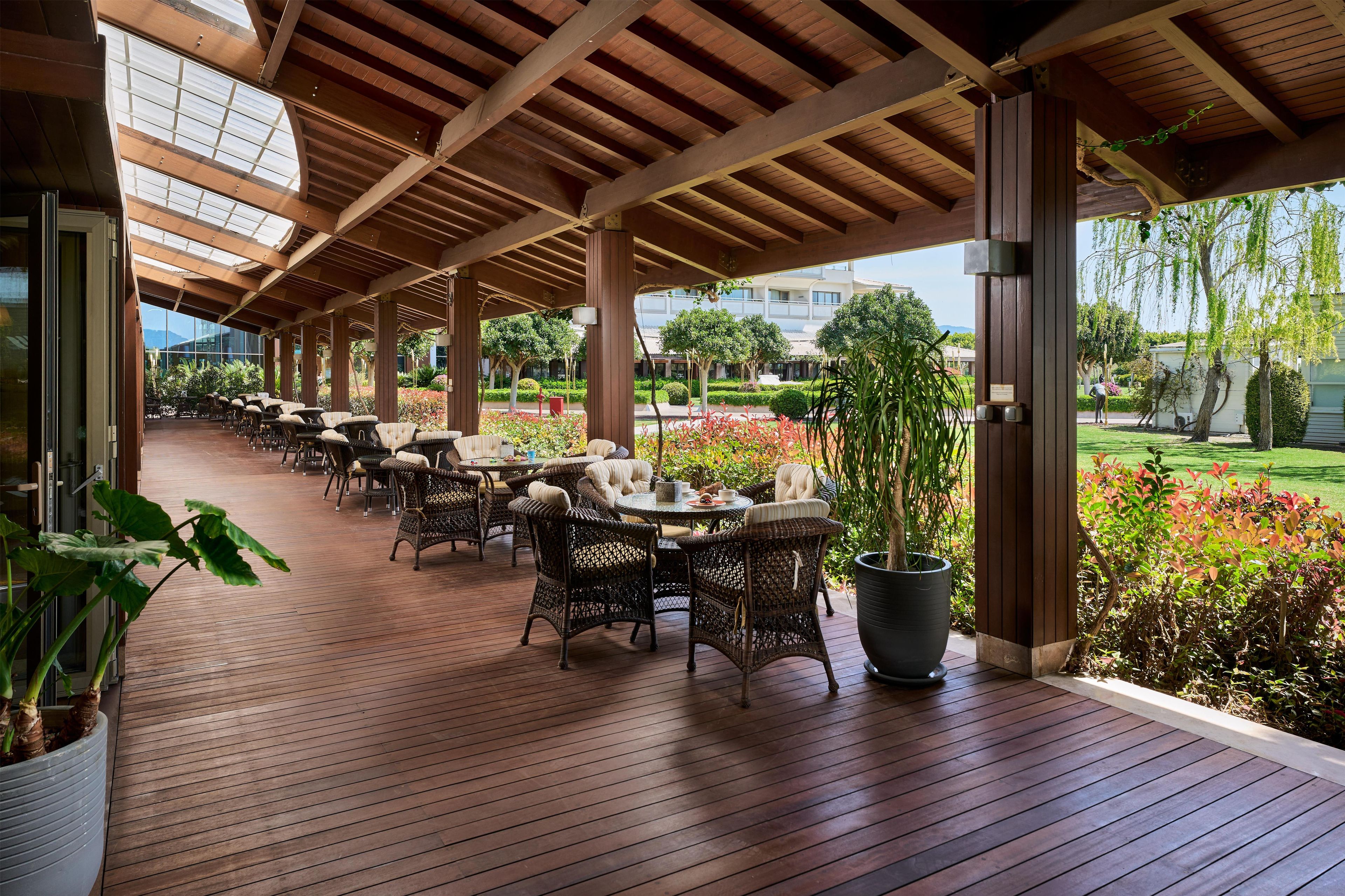 A covered outdoor seating area with wicker furniture and potted plants.