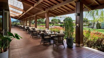 A covered outdoor seating area with wicker furniture and potted plants.