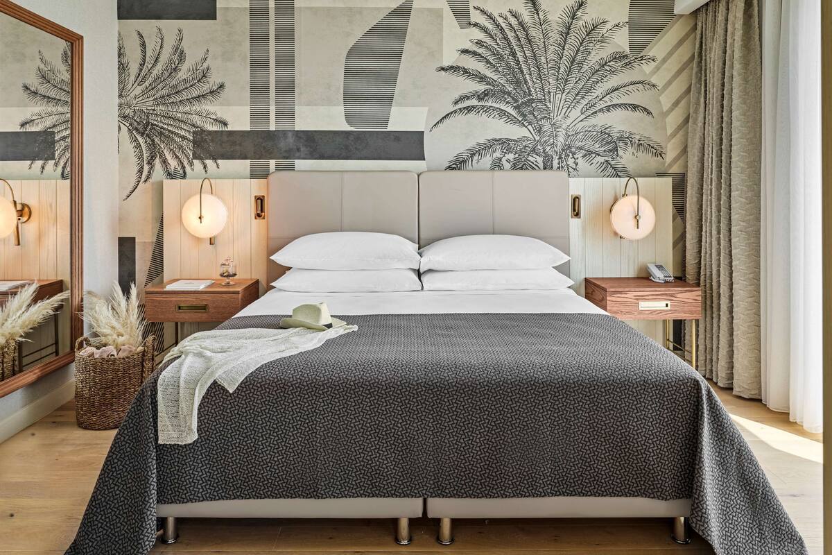 Een moderne slaapkamer met een groot bed, twee nachtkastjes, een hoofdbord met verlichting en een plafondlamp.