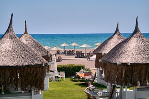 Una località balneare con capanne a tetto di paglia, sdraio e ombrelloni.