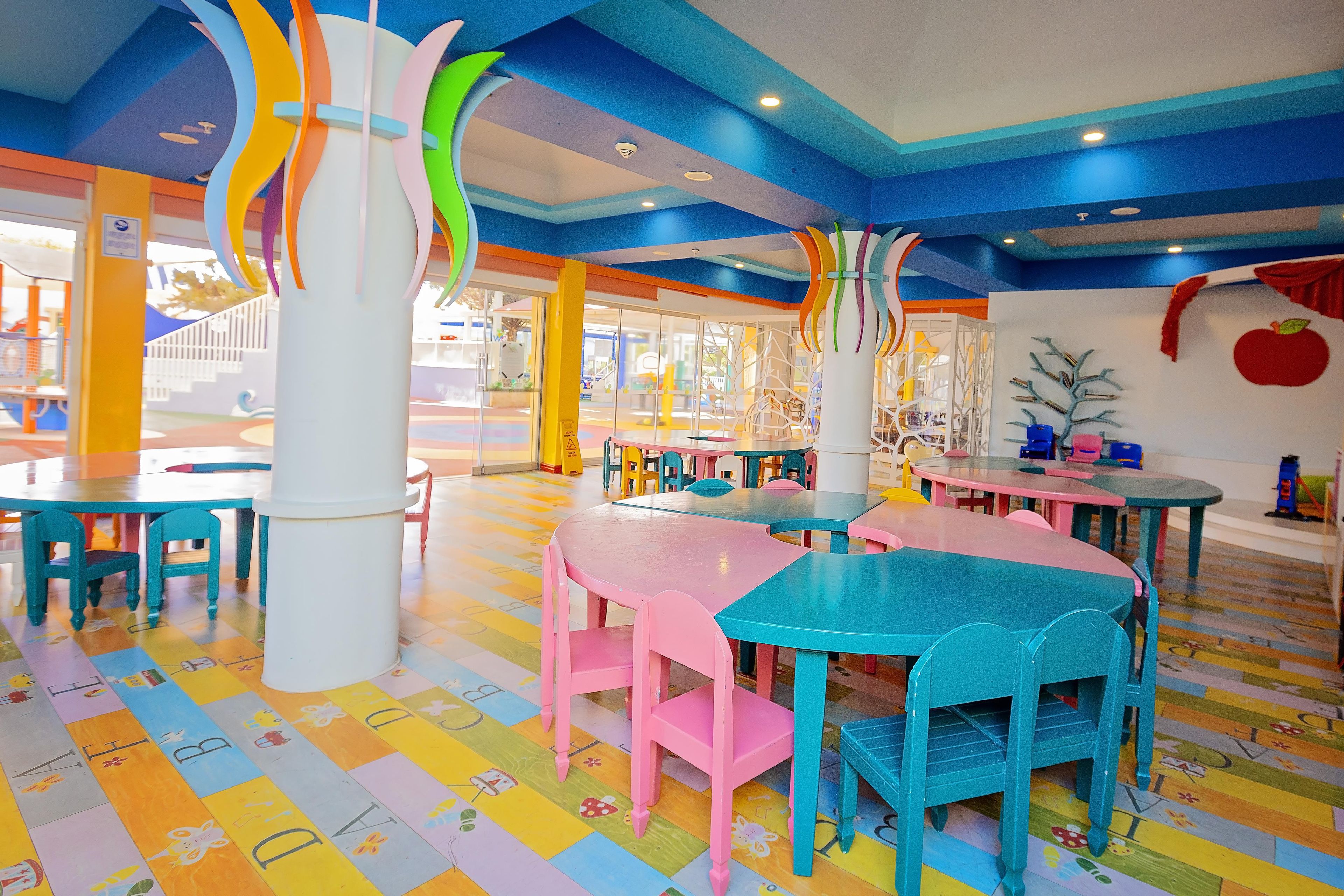 A brightly colored indoor space with tables and chairs arranged for dining.