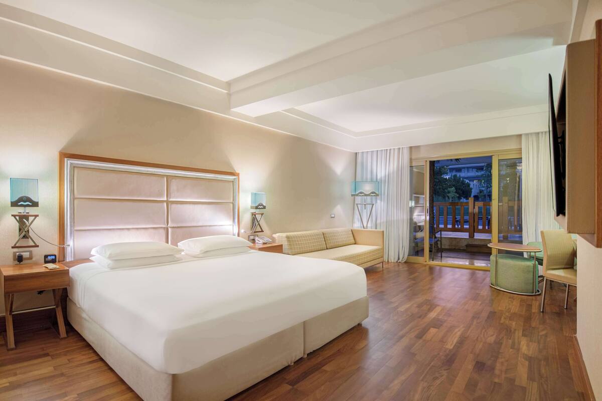 Hotelkamer met een groot bed, een bank, een televisie en een balkon met uitzicht.
