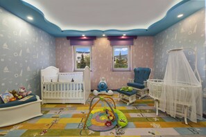 Habitación infantil con cuna, zona de juegos y una silla.