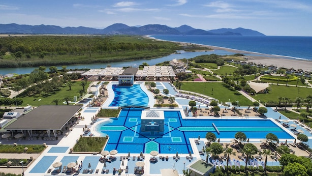 Un complejo turístico con una gran piscina central, varias piscinas más pequeñas y una zona de playa.
