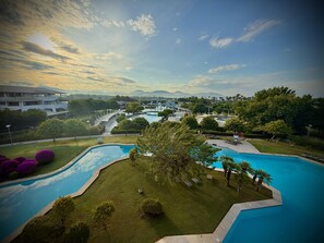Un complexe hôtelier doté d’une grande piscine, d’une végétation luxuriante et offrant une vue sur les montagnes lointaines.