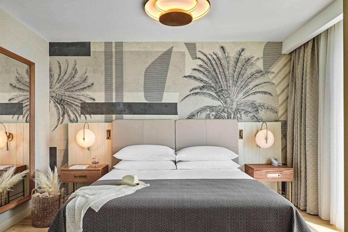 Ein modernes Schlafzimmer mit einem Bett, Nachttischen, Wandkunst und einer Deckenleuchte.