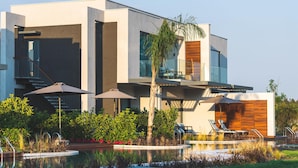 Una casa moderna de dos pisos con piscina, mobiliario exterior y una escalera.