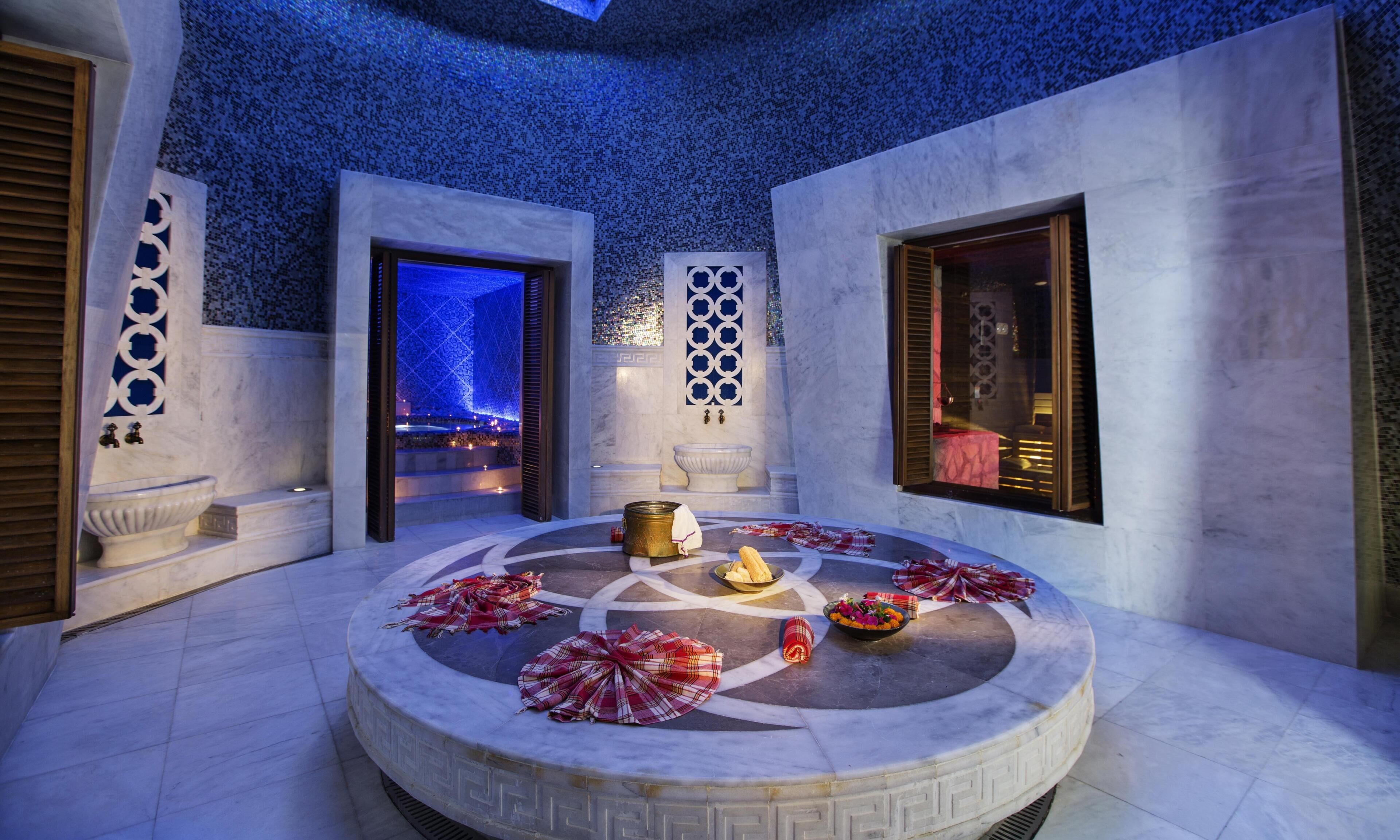 Un área de spa con un jacuzzi circular, una pared decorativa y una ventana con persianas.