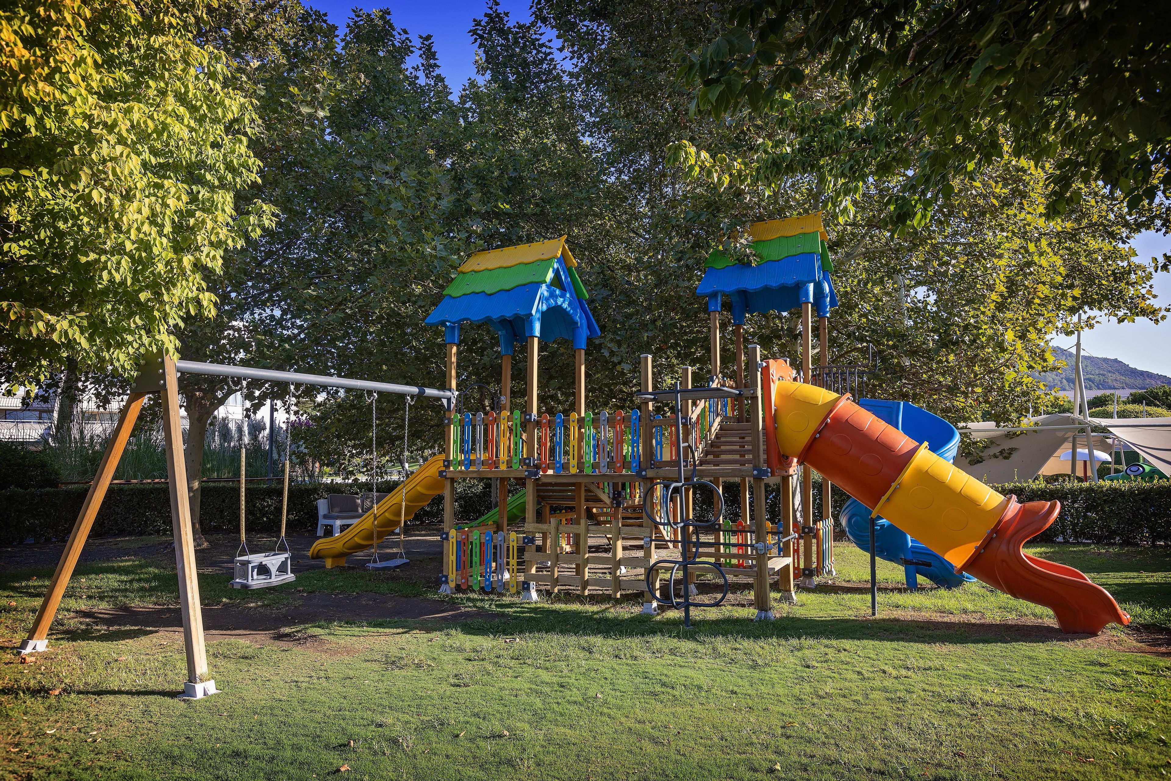 Un parque infantil con tobogán, columpios y una estructura para escalar.