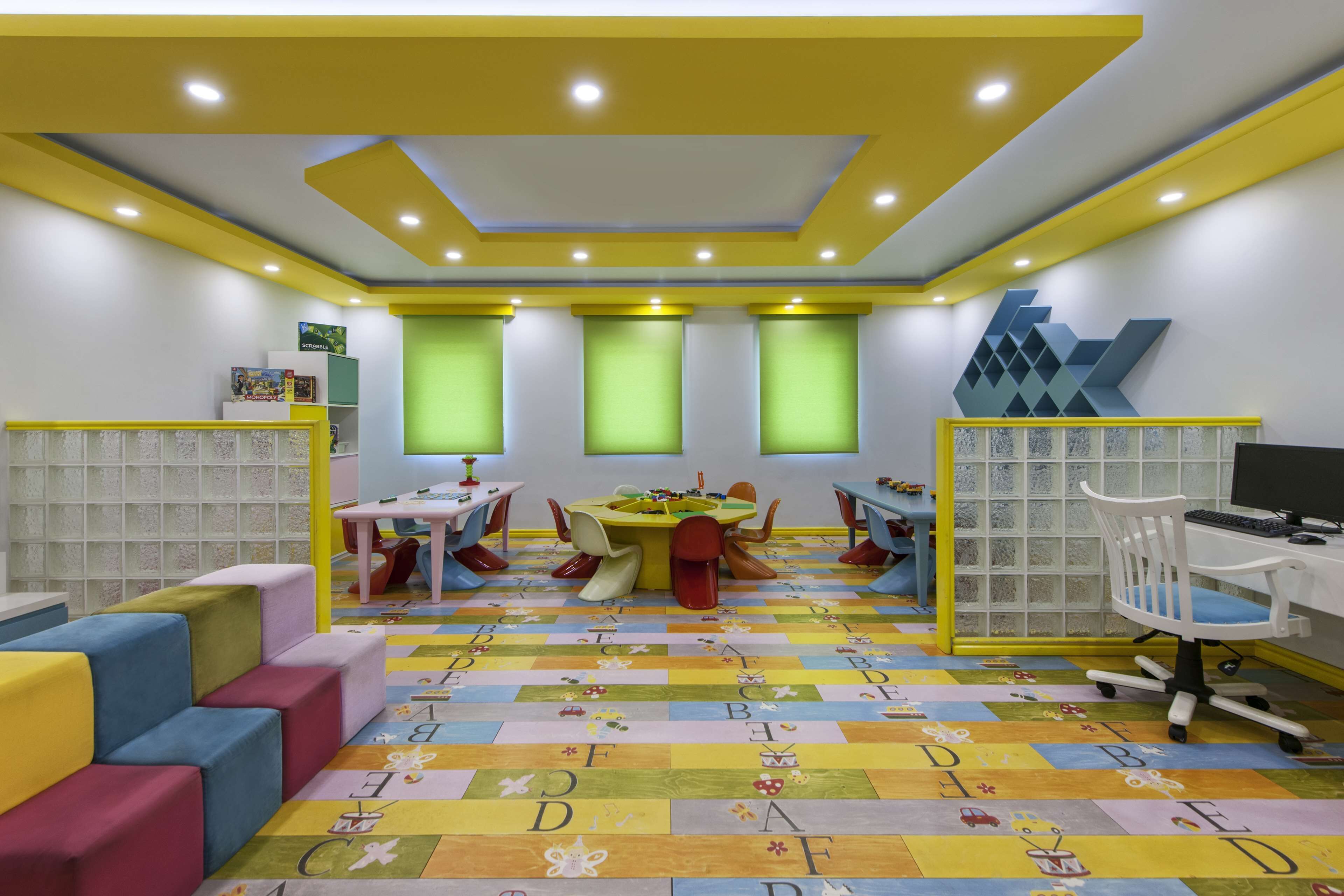 Una sala de juegos infantil con muebles coloridos, una mesa de juegos y juguetes educativos.